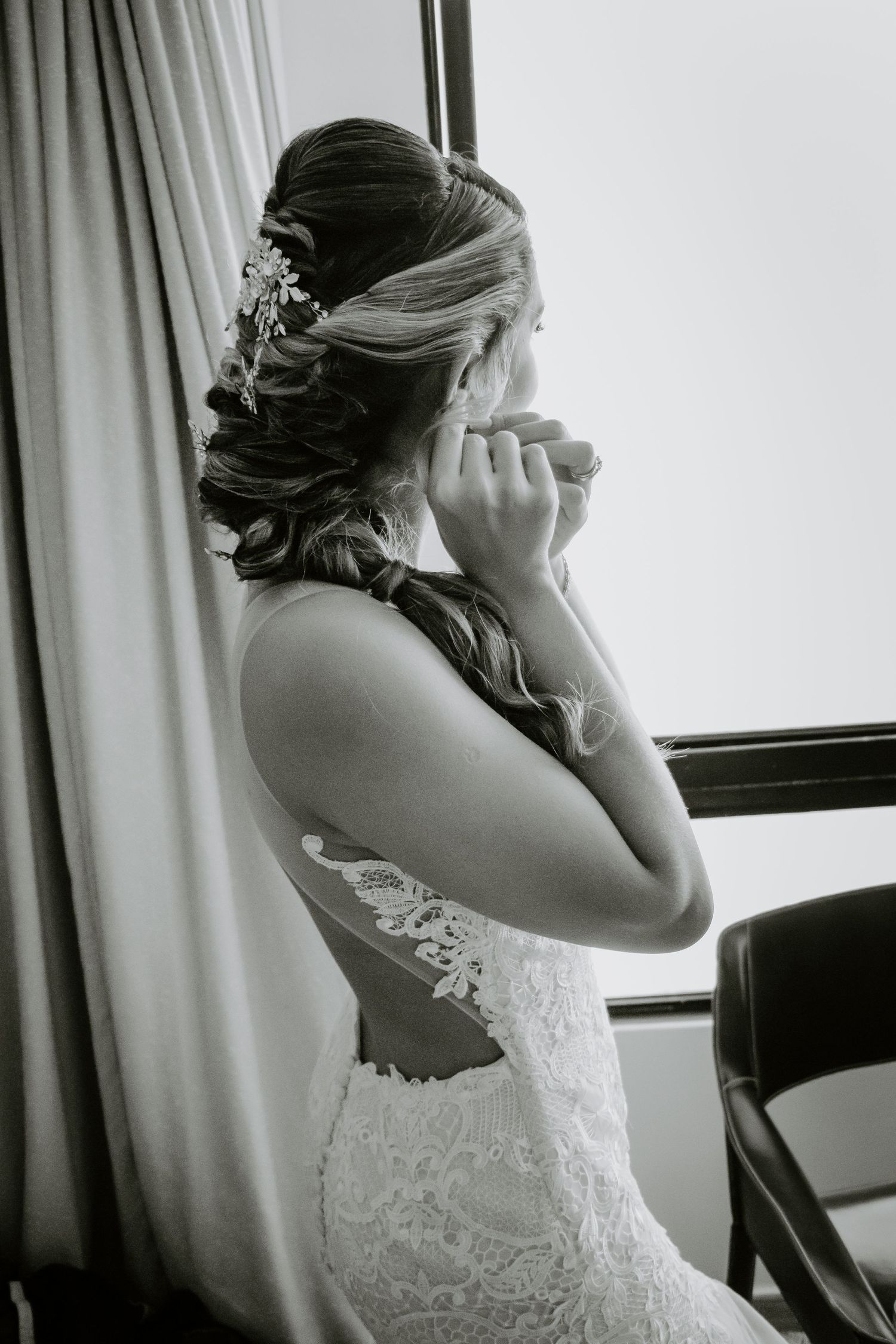 Side profile of bride in lace dress with elegant updo and hair accessories.