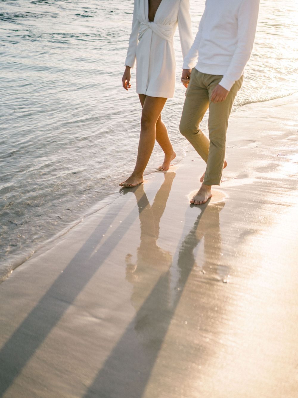 Pieds d'un couple qui marche dans l'eau sur une plage
