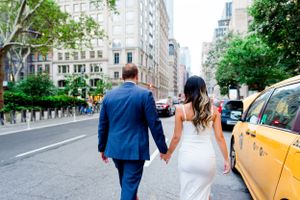 engaged couple holding hands walking through Flatiron District NYC next to yellow taxi