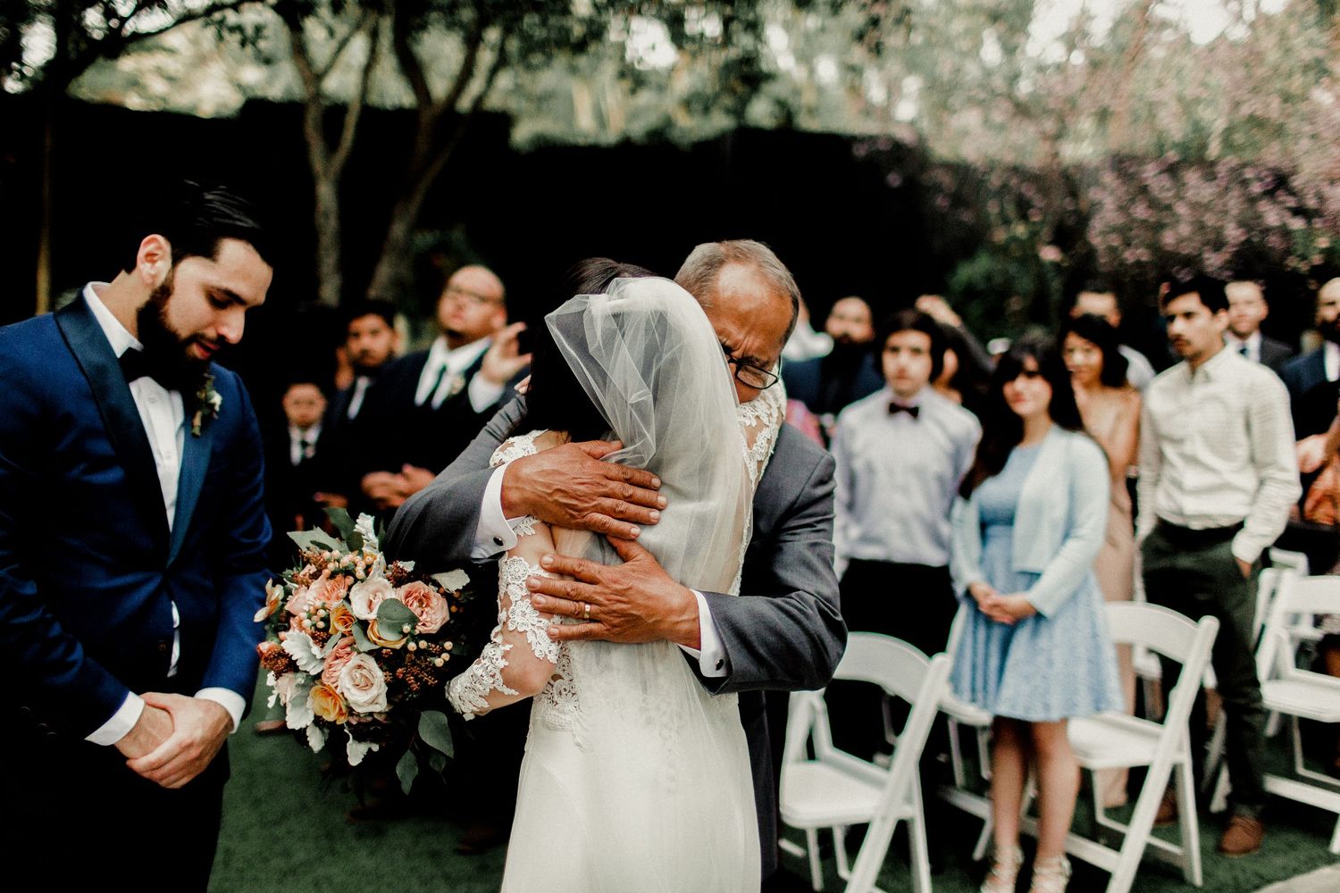 bride giving hug to father as he passes her off