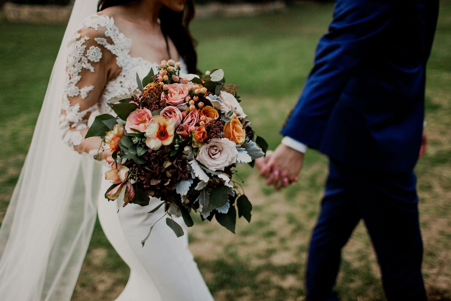 detail shot of bride dress and bouquet while walking