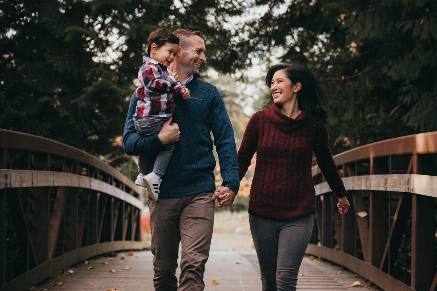 mom, dad and toddler boy laughing and walking on bridge at dahlia park in Issaquah, WA by Shutterbabe Snaphots
