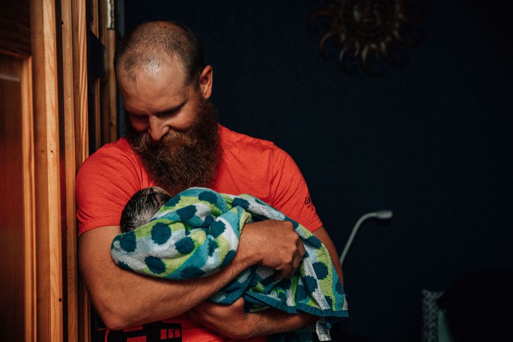 New dad smiles at his newborn baby after a home birth in Northwest Arkansas