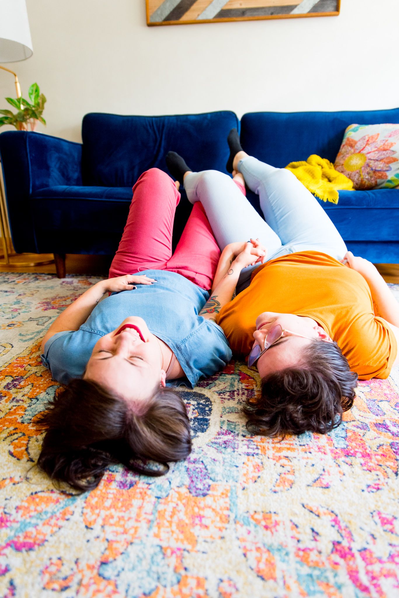married same sex couple laying on pink and orange rug with feet on blue couch for chicago couples pictures