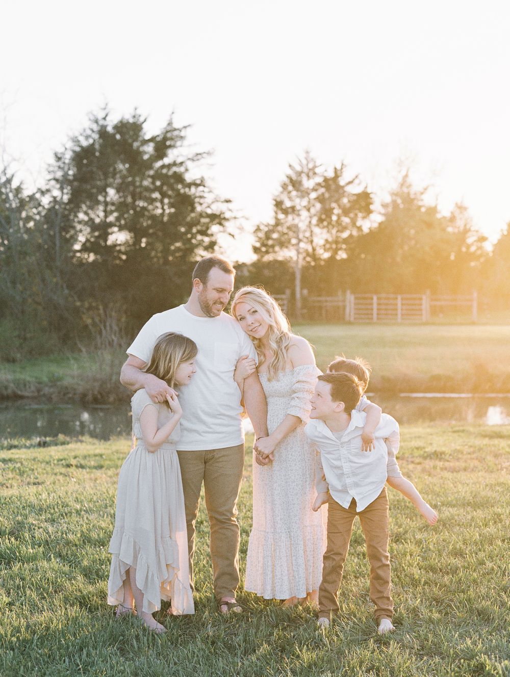 Family snuggles close together at sunset as mom looks at camera