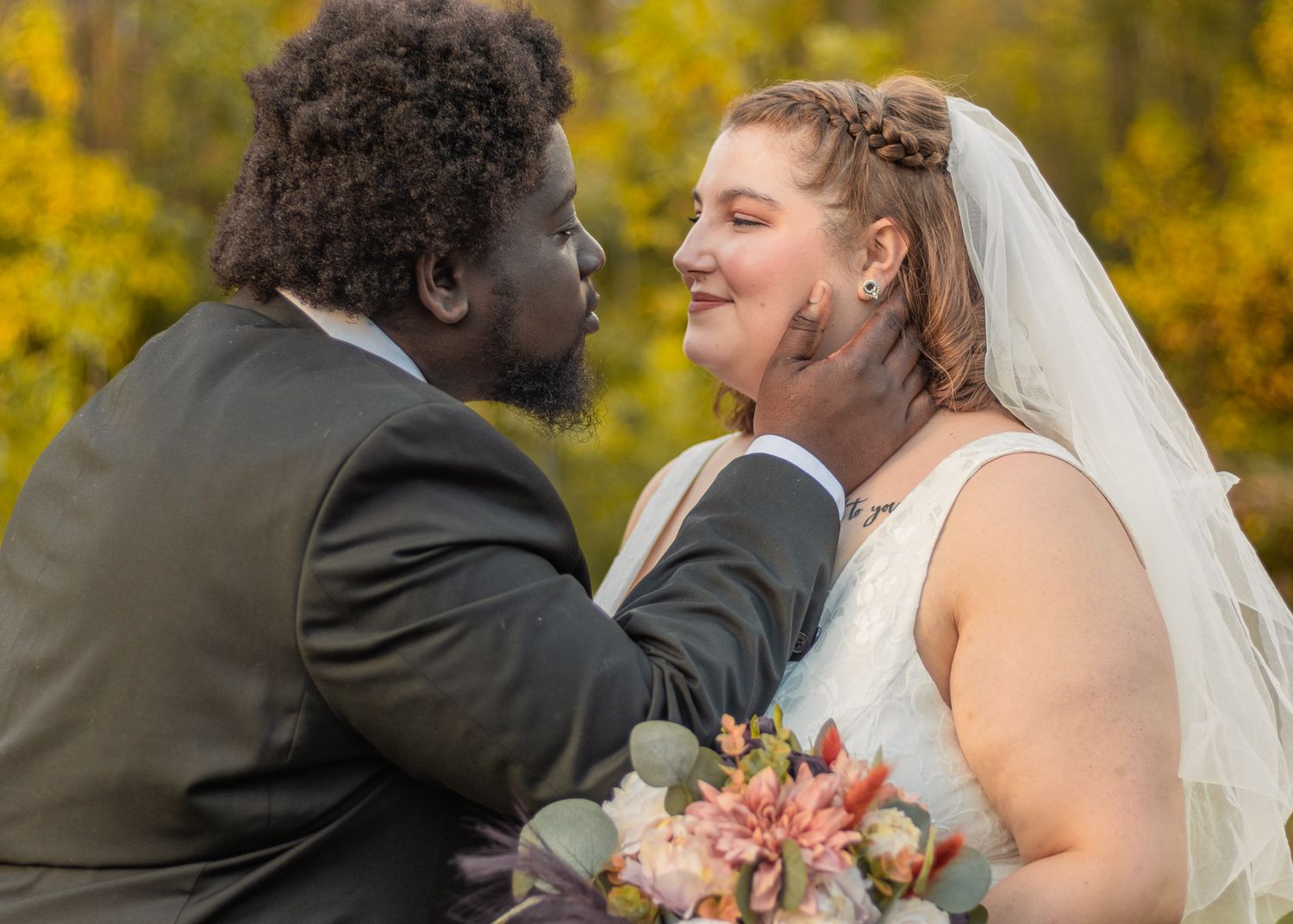 A tender moment between newlyweds sharing an intimate gesture during their outdoor wedding.