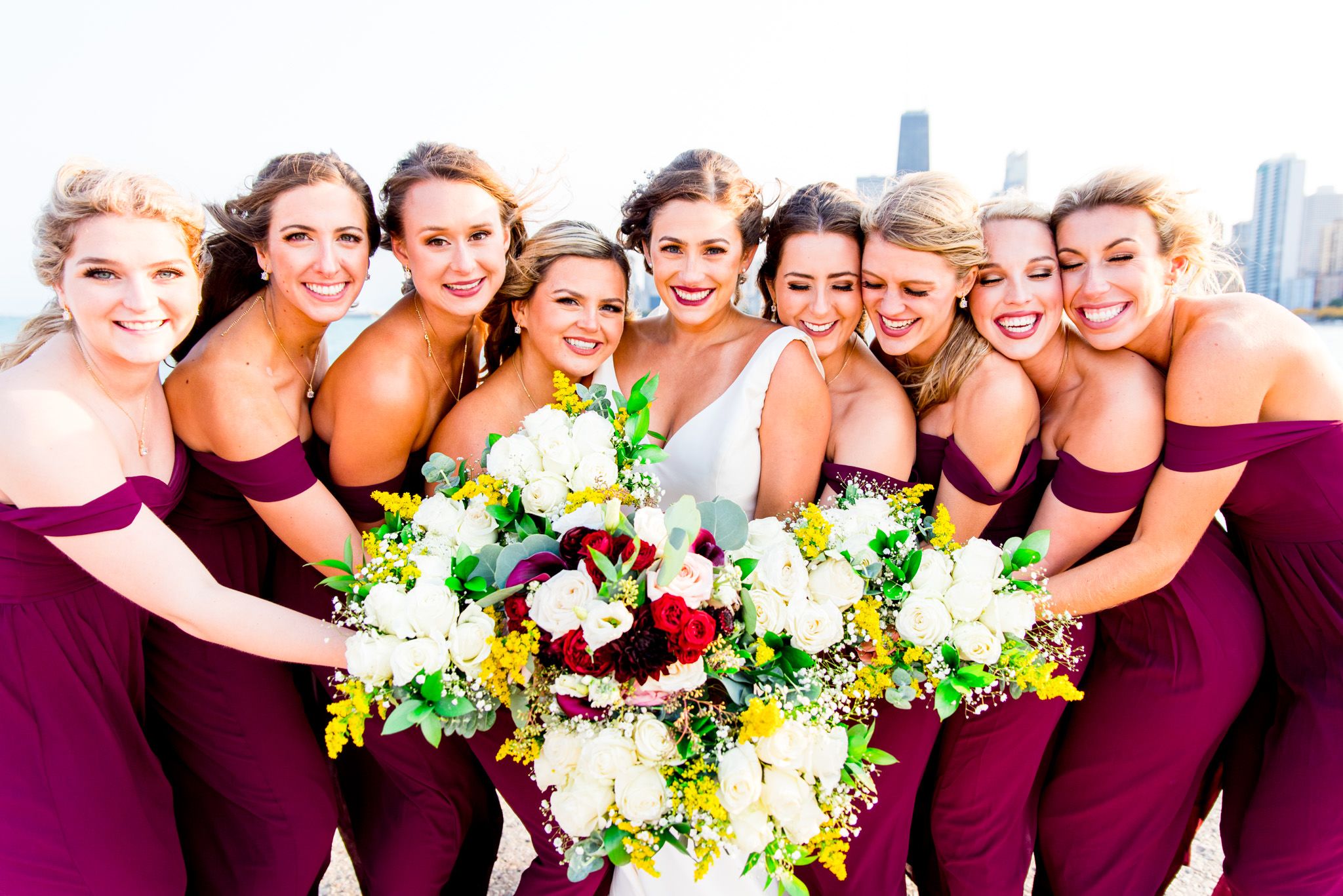 smiling bridesmaids huddle for photo with bride in front of chicago buildings