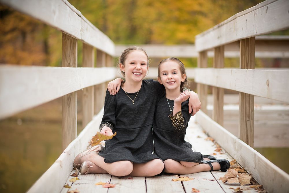 Portrait of two sisters sitting together on a footbridge in Morgantown, WV taken by photographer Laura Priestley