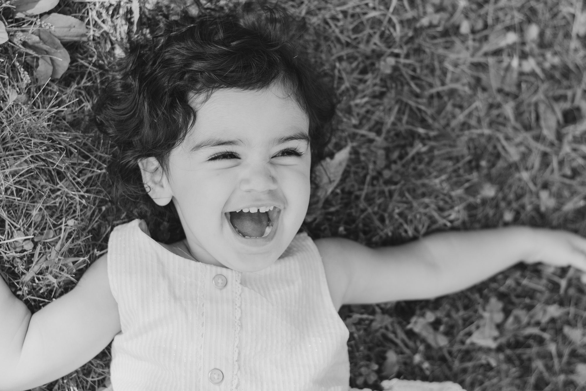 Toddler laughing in grass in black and white in Pittsburgh, Pennsylvania