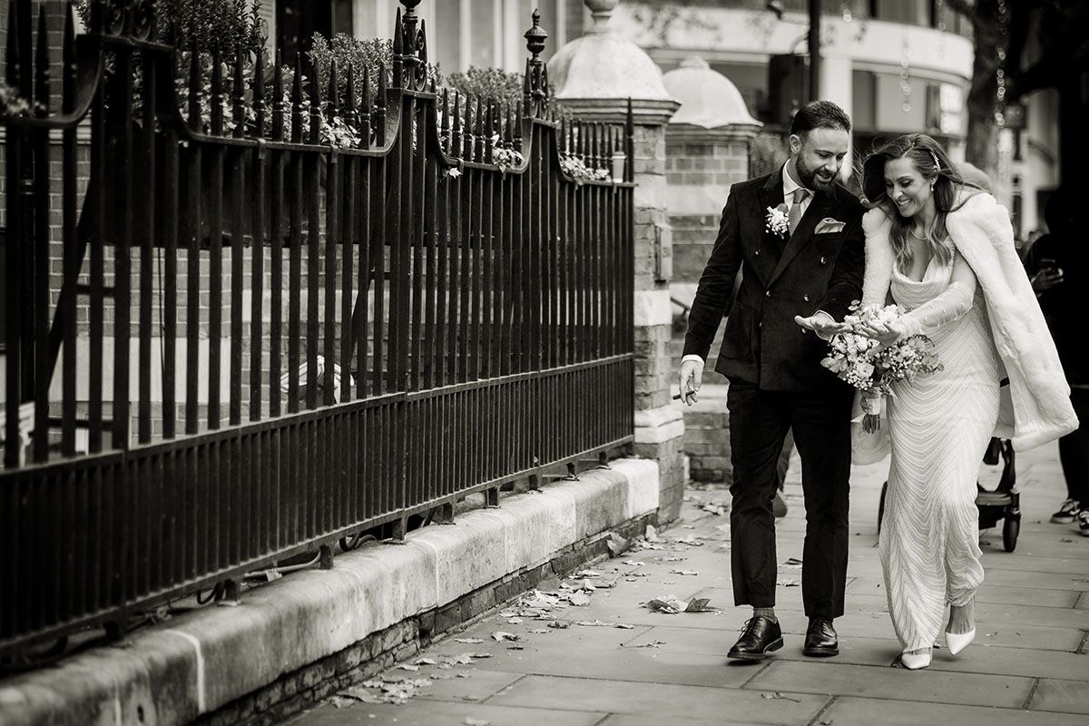 Bride and groom in Central London, looking at their wedding rings whilst walking.