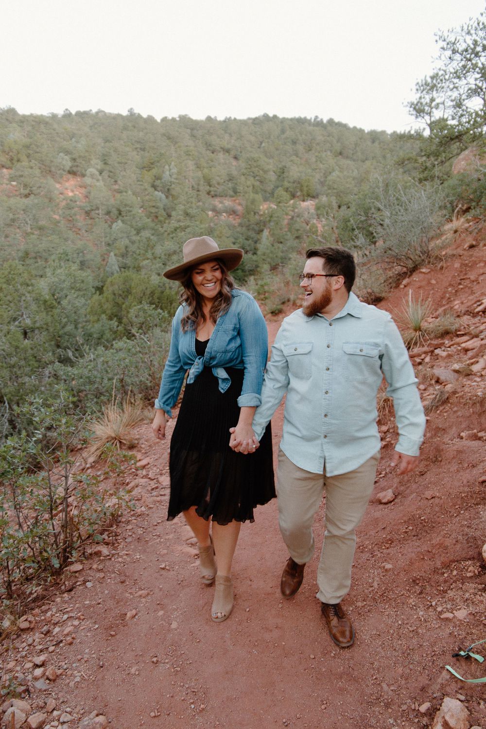 couple bumping hips on a trail in garden of the gods after getting engaged