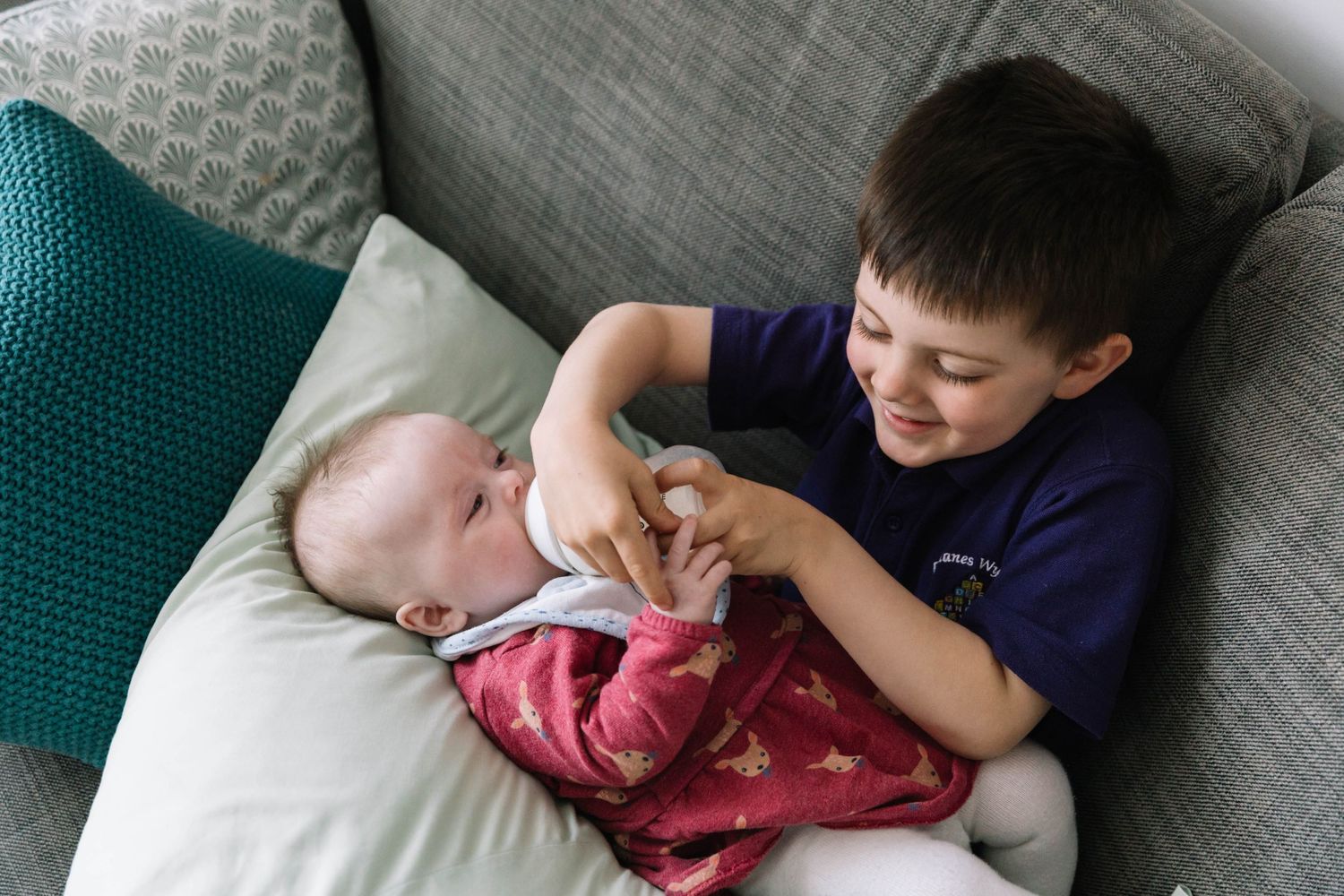 brother feeding baby sister milk from bottle