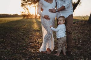 A boy looking at the camera standing next to his pregnant mother for her maternity shoot in Perth Western Australia