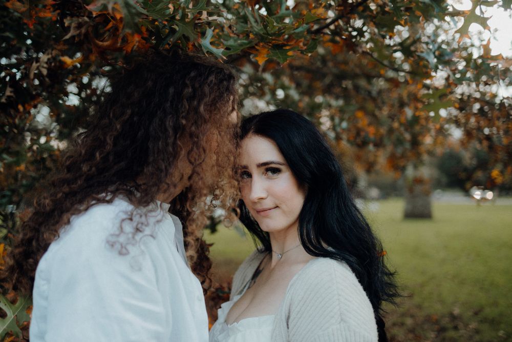 A romantic couple shares an intimate moment against a backdrop of fall foliage.