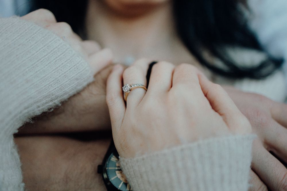 Close-up shot of hands with an engagement ring in soft sweater sleeves.
