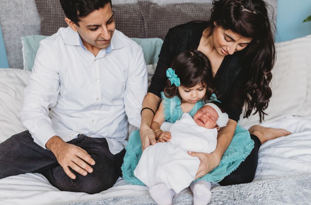 Parents and little sister holding newborn in their bedroom during Chicago Lifestyle newborn session