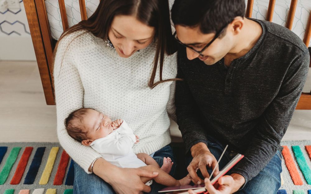 new parents reading to their son in home Chicago newborn lifestyle photography session