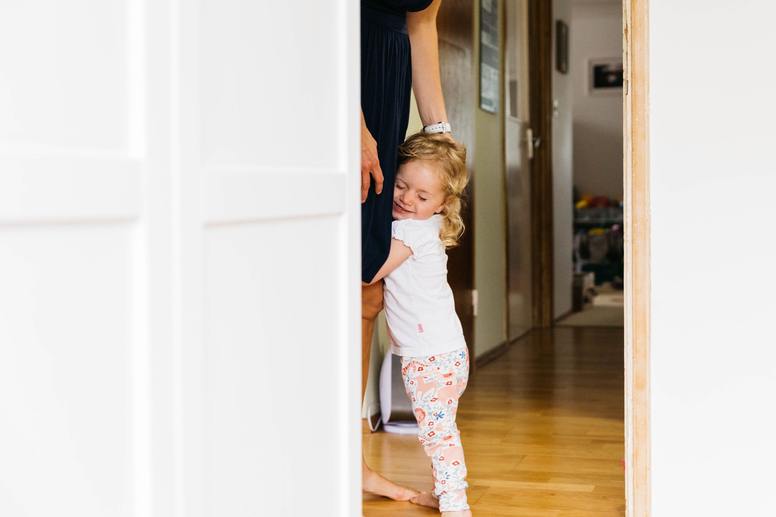 little girl eyes closed grabbing mum leg