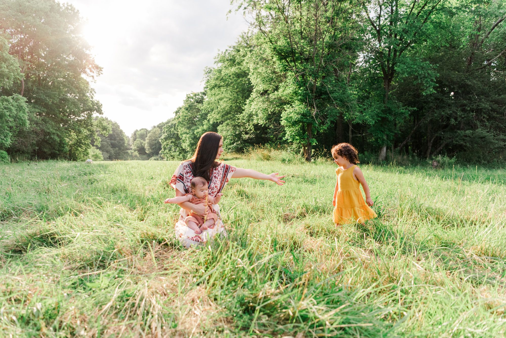 Mother reaching for daughter in golden hour sunlight in Pittsburgh, Pennsylvania