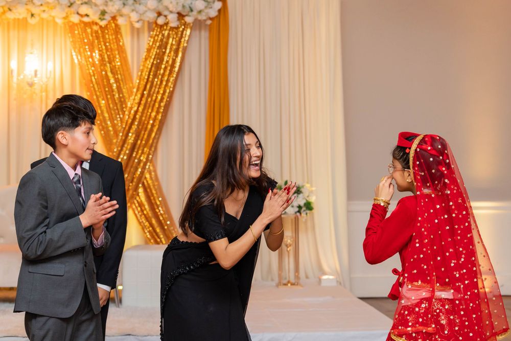 Three people sharing a joyful moment during a celebration with gold decorative backdrop.