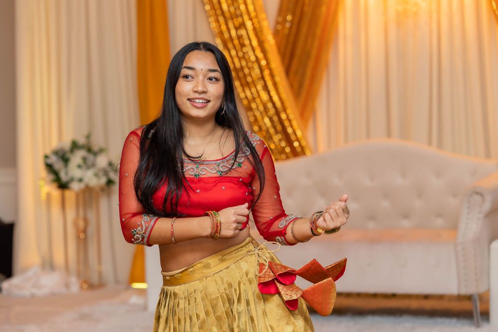 Dancer in red and gold attire performs expressive moves at an elegant venue.