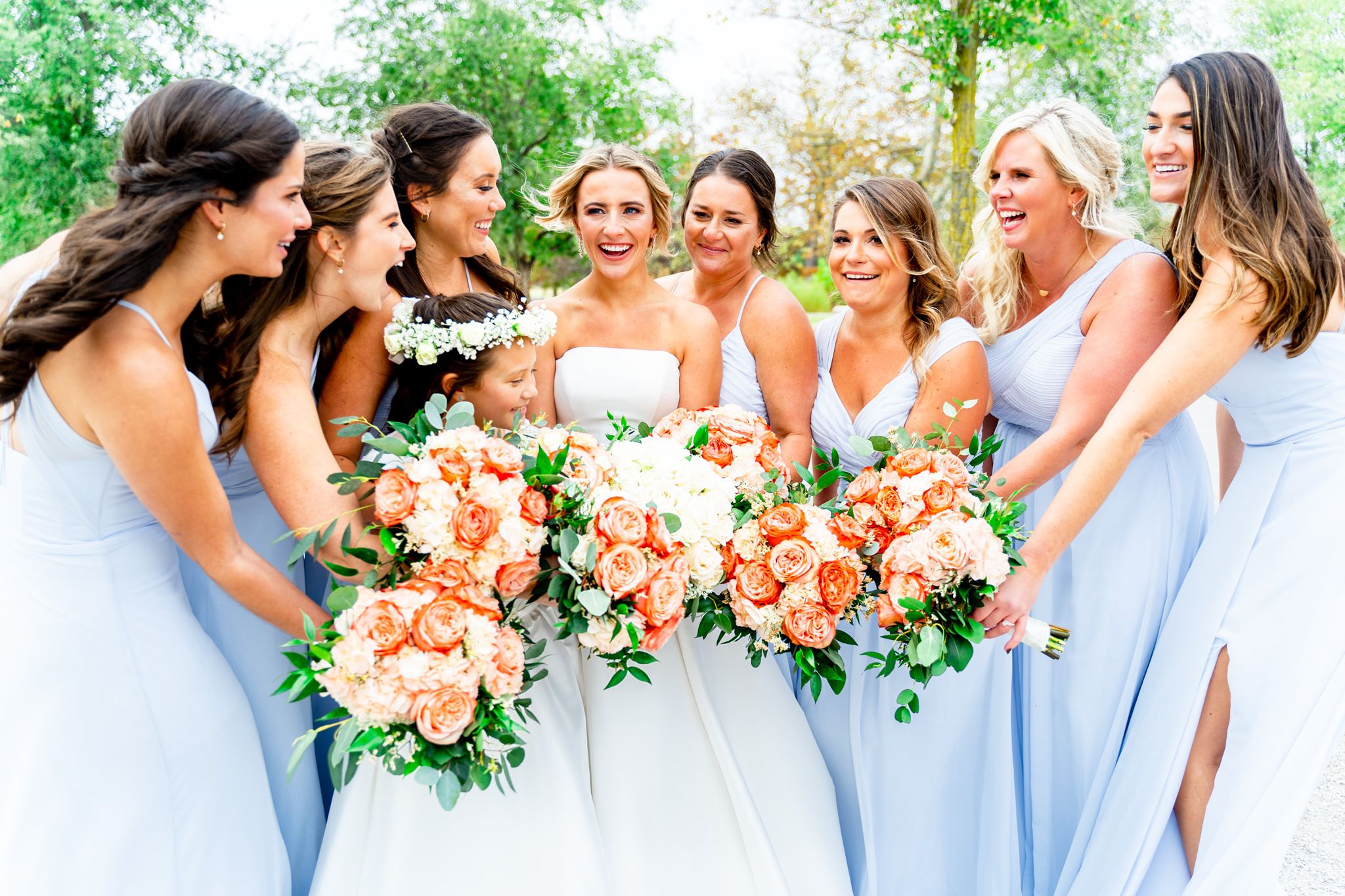 bride laughs with bridesmaids in light blue dresses and coral bouquets at STL Forest Park fall wedding