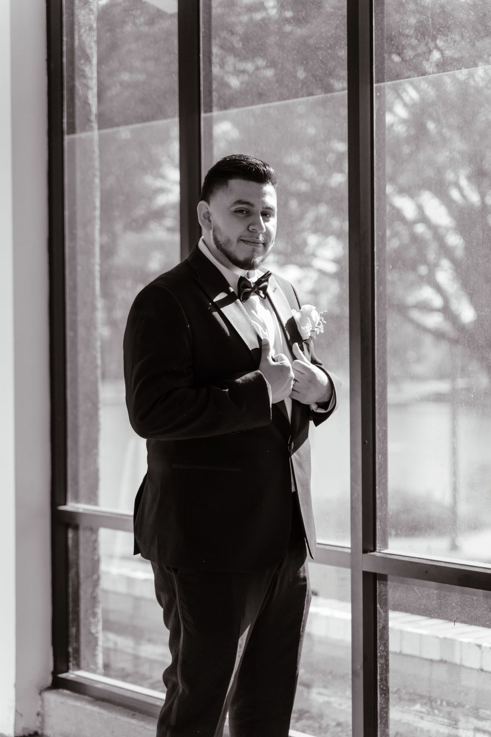 Black and white photo of groom smiling at camera, taken by Southern CA photographer Melina Garcia