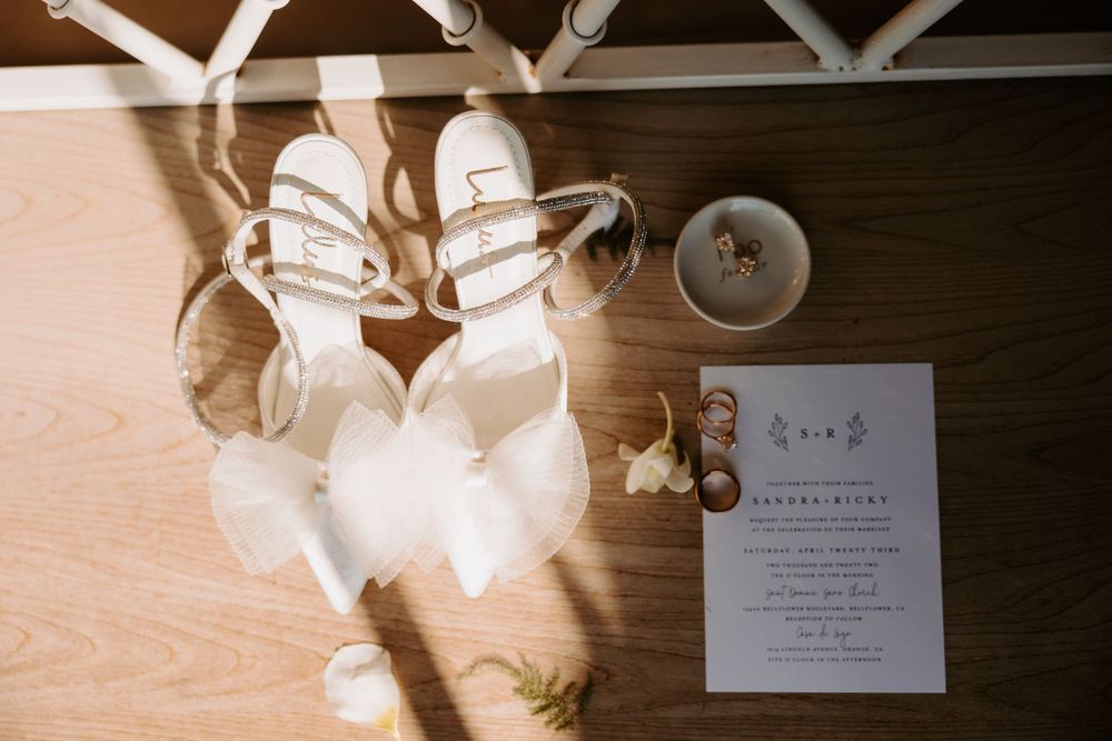Flat-lay shot of bride's shoes, wedding rings and invitations, taken by LA wedding photographer Melina Garcia