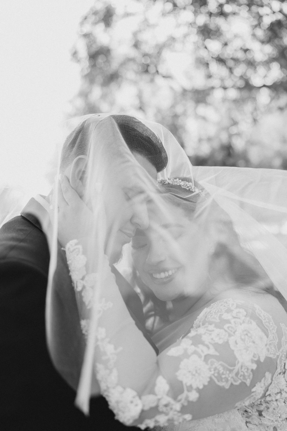Black and white photo of bride and groom under sheer veil at Casa de Lago
