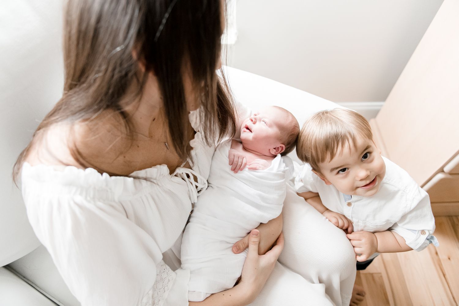 Big brother smiles up mischievously next to his baby sister