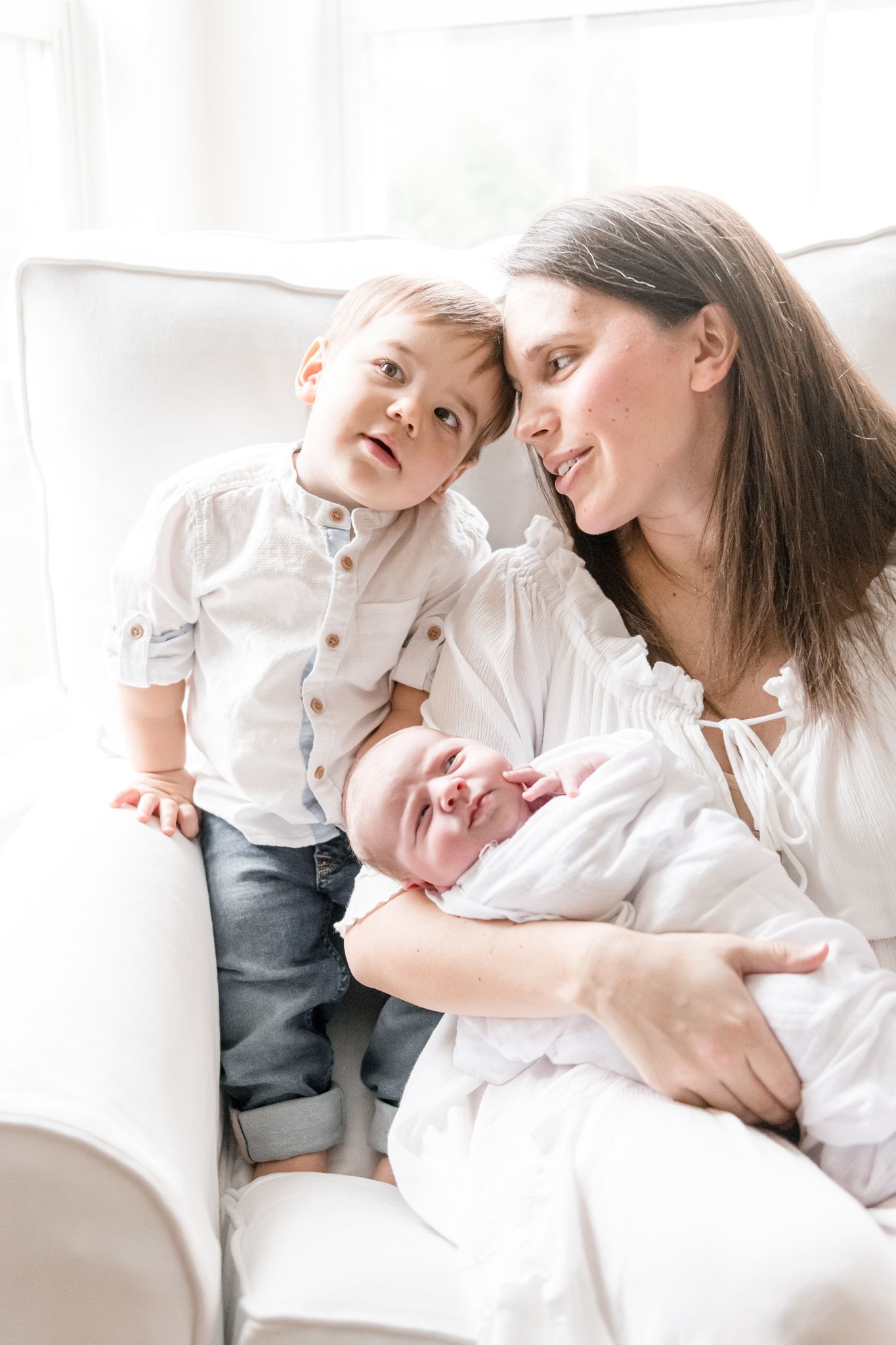 Mother rests head on her toddler son while holding her new baby girl