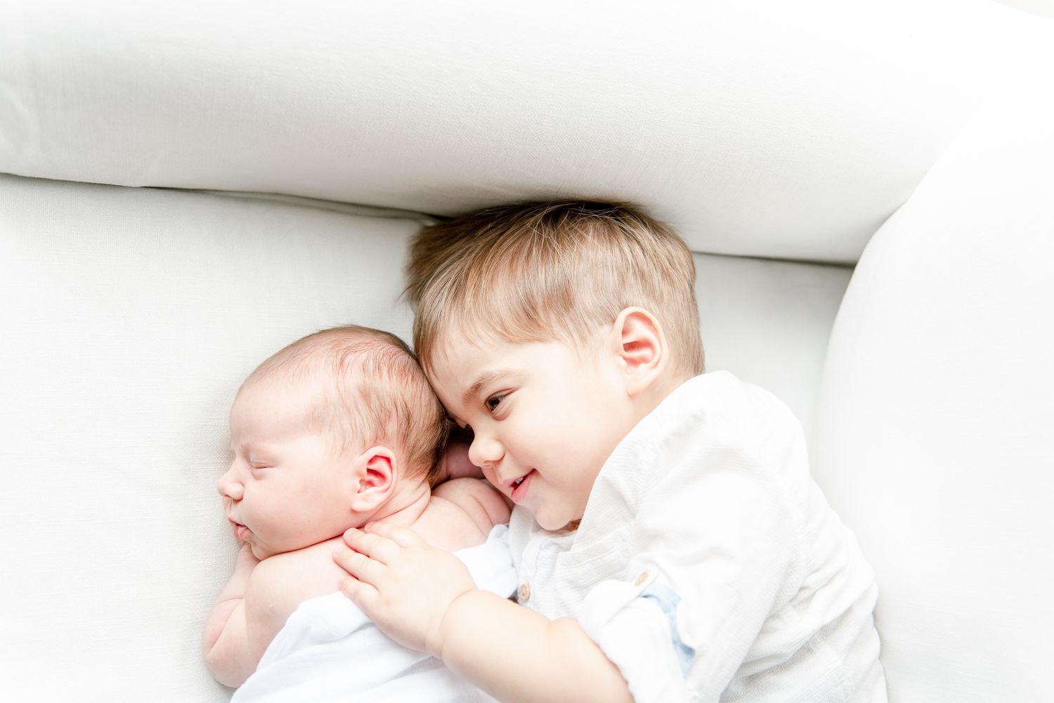New big brother cuddles with his baby sister