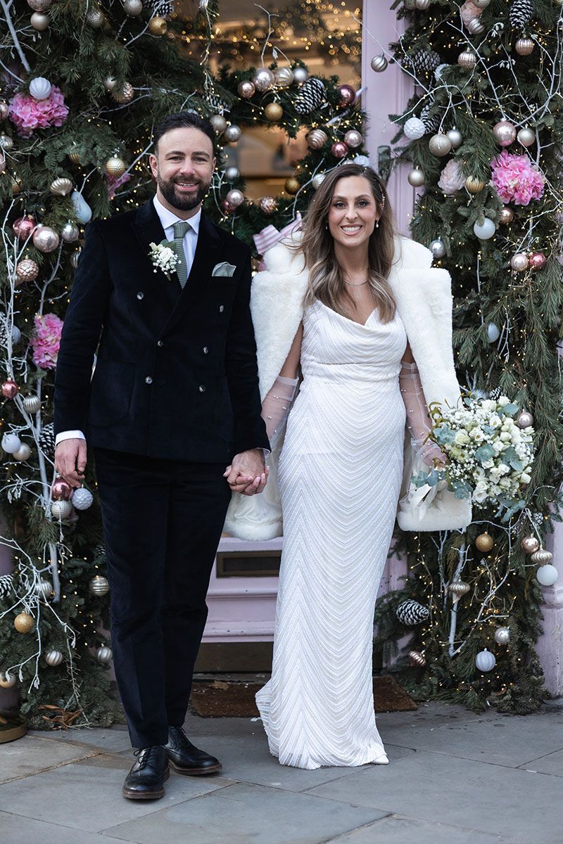 Bride and groom standing outside Peggy Porschen's entrance full of pink roses.