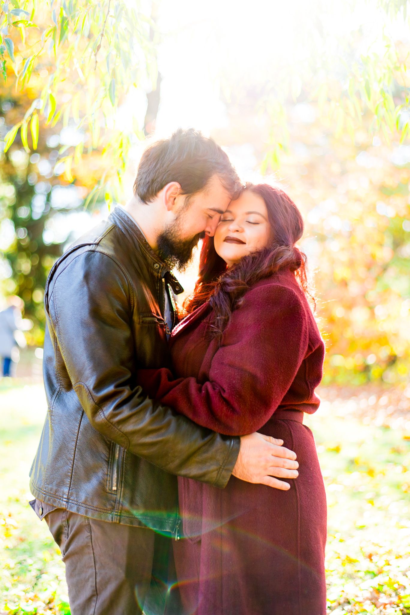 brown hair man holding woman with red hair in matching red coat, smiling at sunrise in Central Park