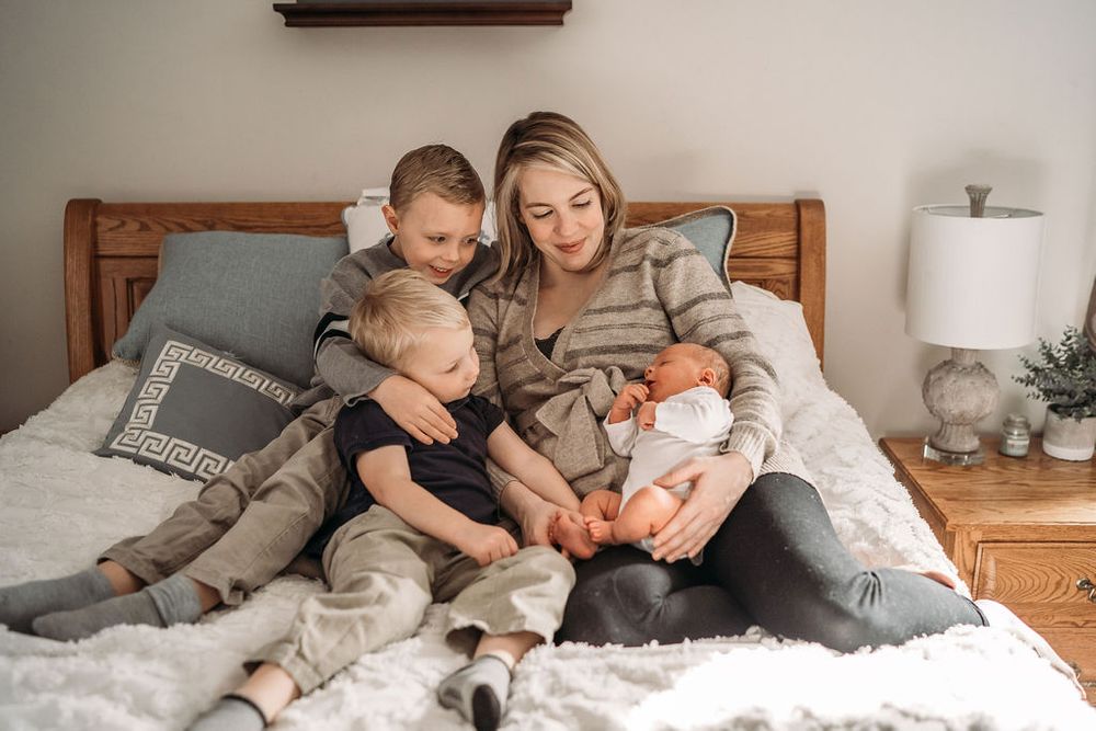mom holding her three boys in her boston bedroom