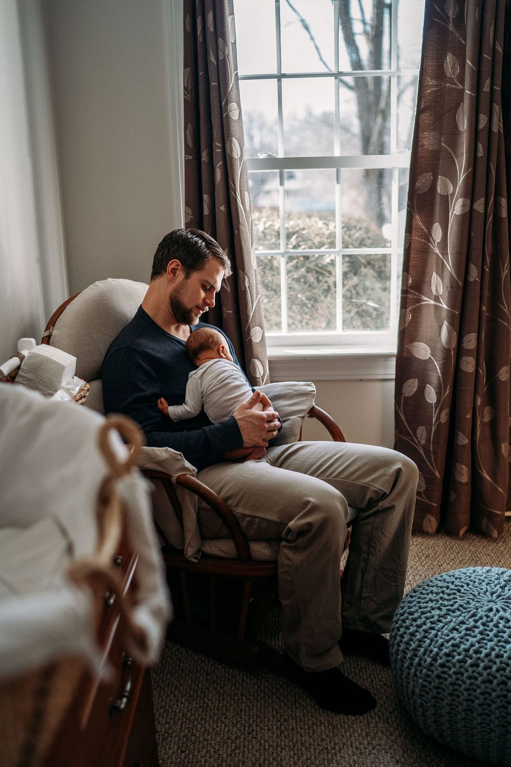 dad rocking his newborn in the nursery of their boston home