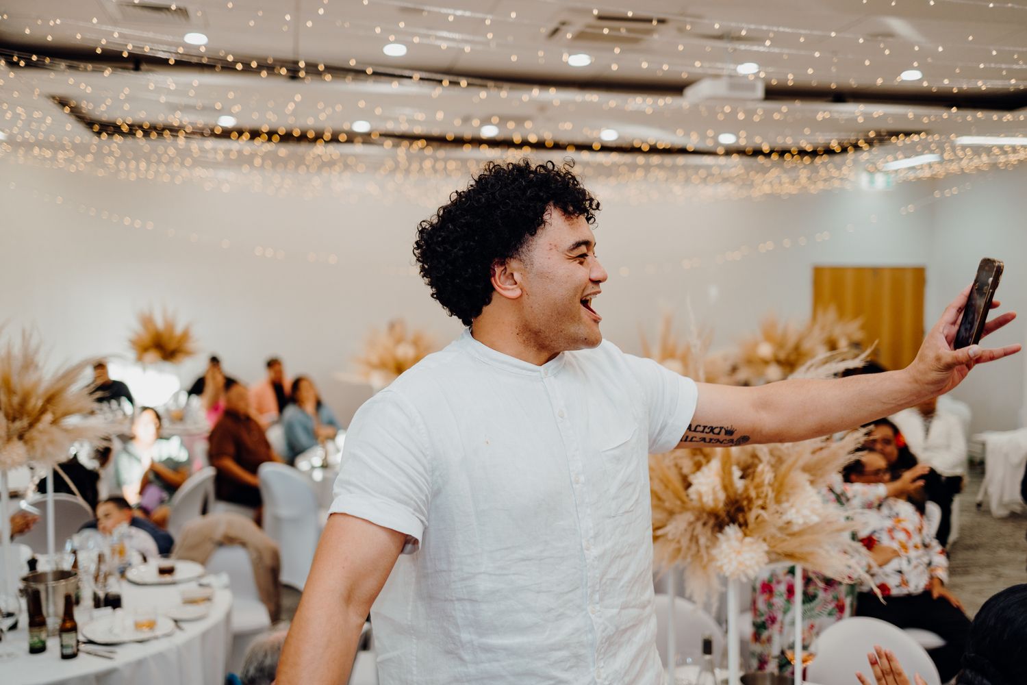Enthusiastic guest celebrating at wedding reception decorated with dried palm accents.