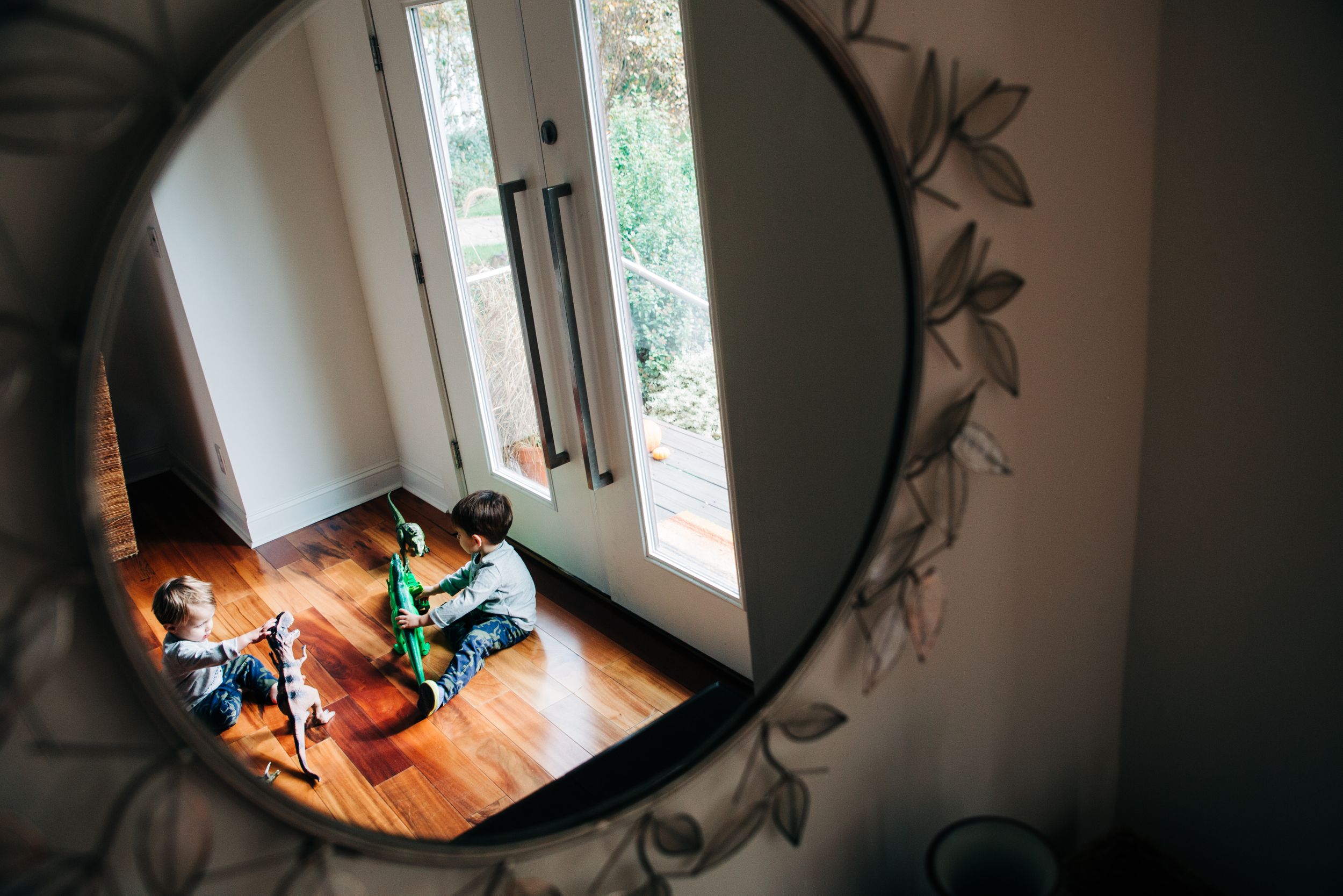 Mirror reflection of two young boys playing with their dinosaur toys in the foyer of their Charlotte home