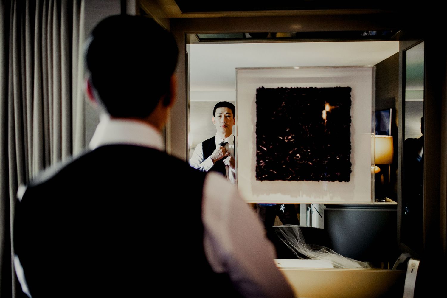groom adjusting suit in front of mirror