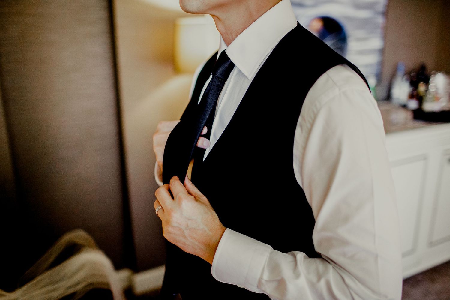 groom adjusting tie next to mirror