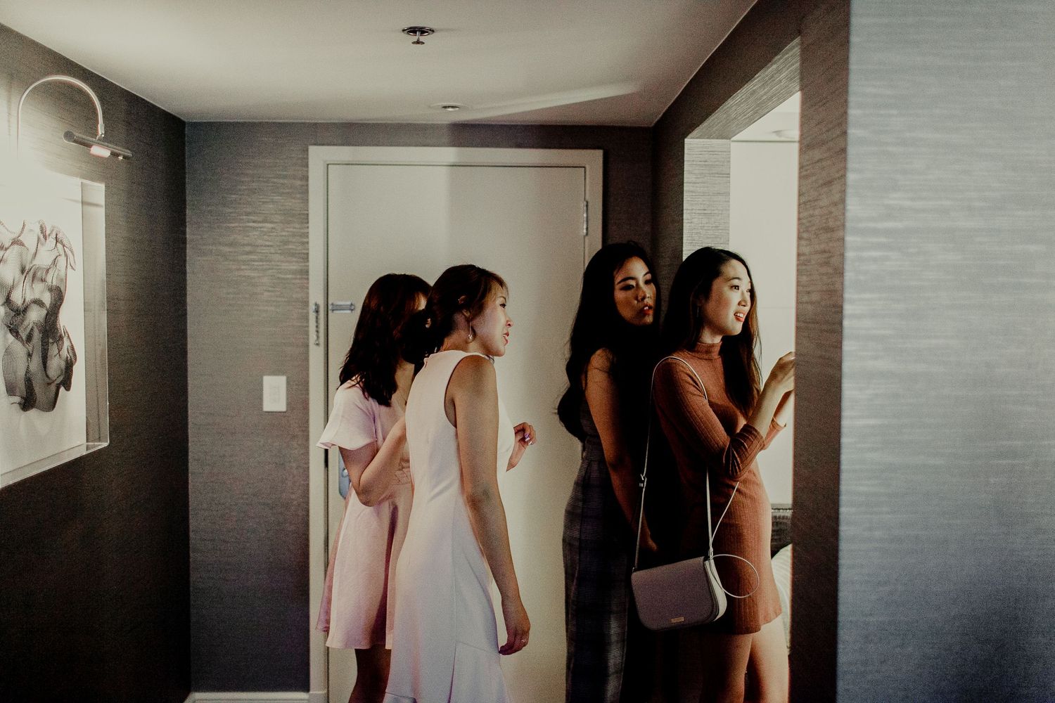 bridal party watching and helping bride prepare makeup and hair inside hotel