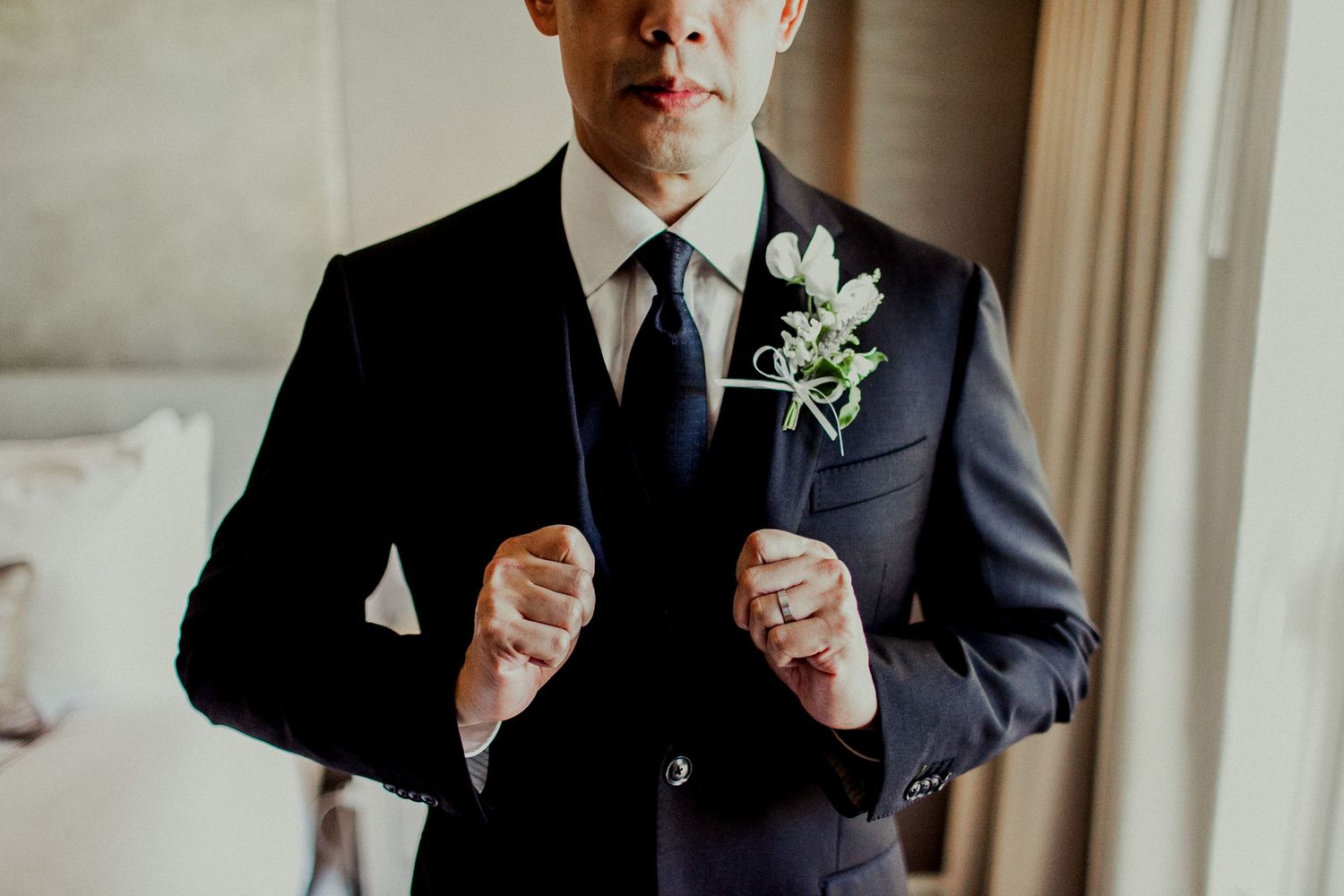 groom showing wedding ring and suit
