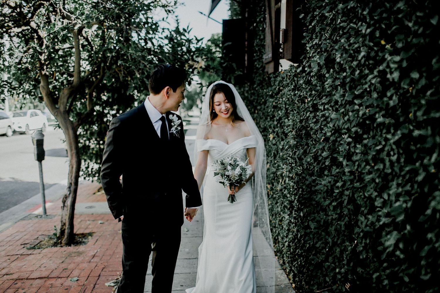 bride and groom walking on sidewalk with leaf wall side of a.o.c. la