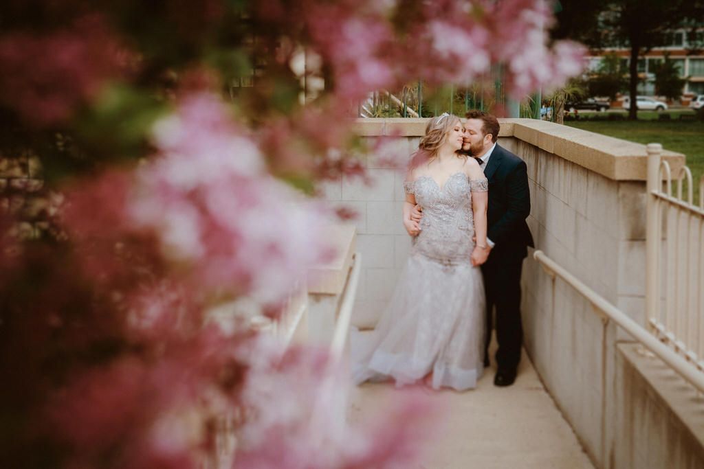 Spring wedding portraits with pink cherry blossoms in the foreground.