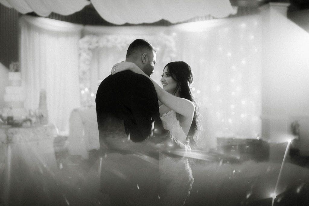 An artistic black and white wedding portrait with dramatic lighting and misty atmosphere.