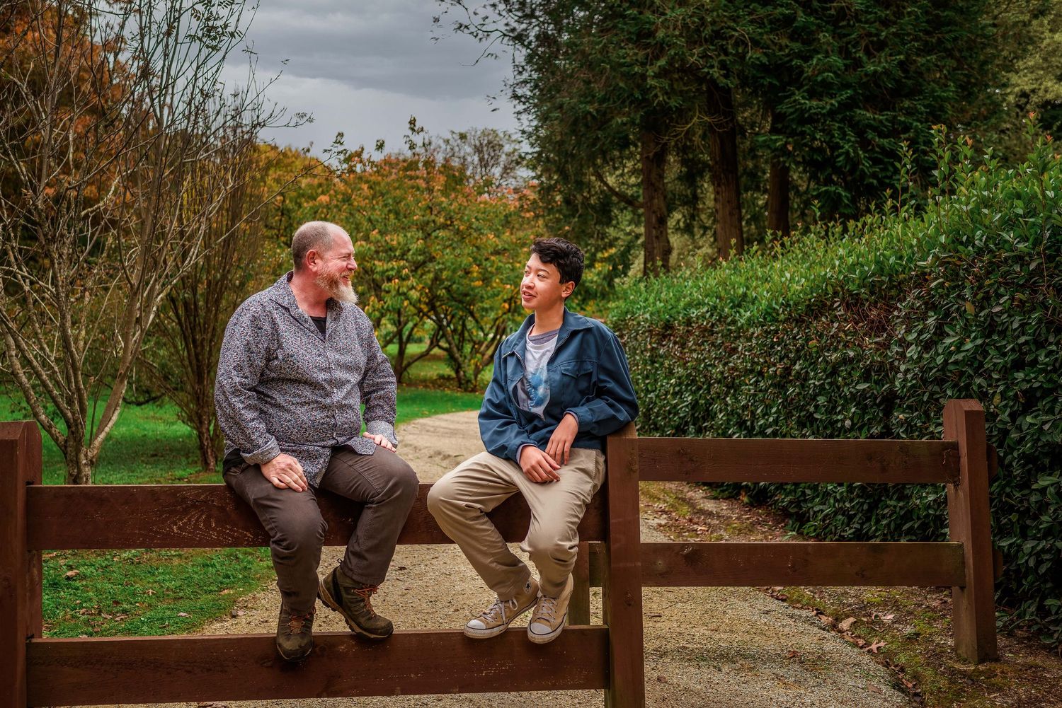 Father and son sitting on fence talking