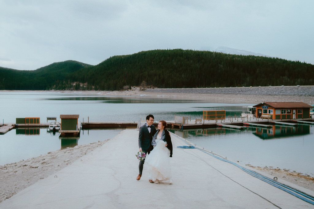 Lakeside dock wedding photos with mountain backdrop and calm waters.