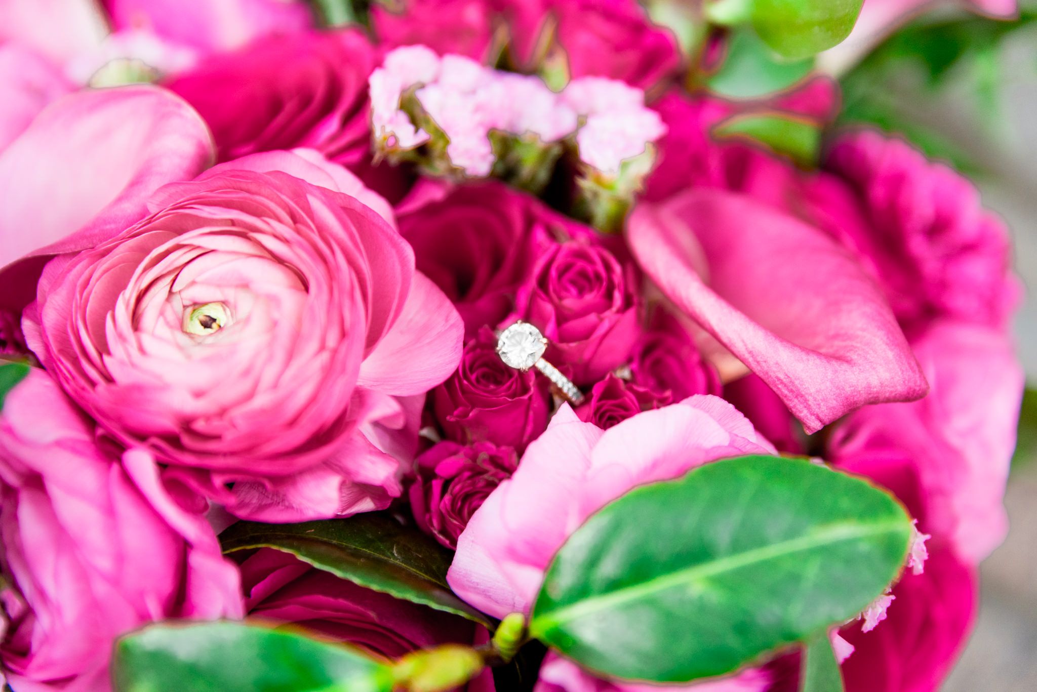 diamond engagement ring sitting in bouquet of pink ranunculus flowers