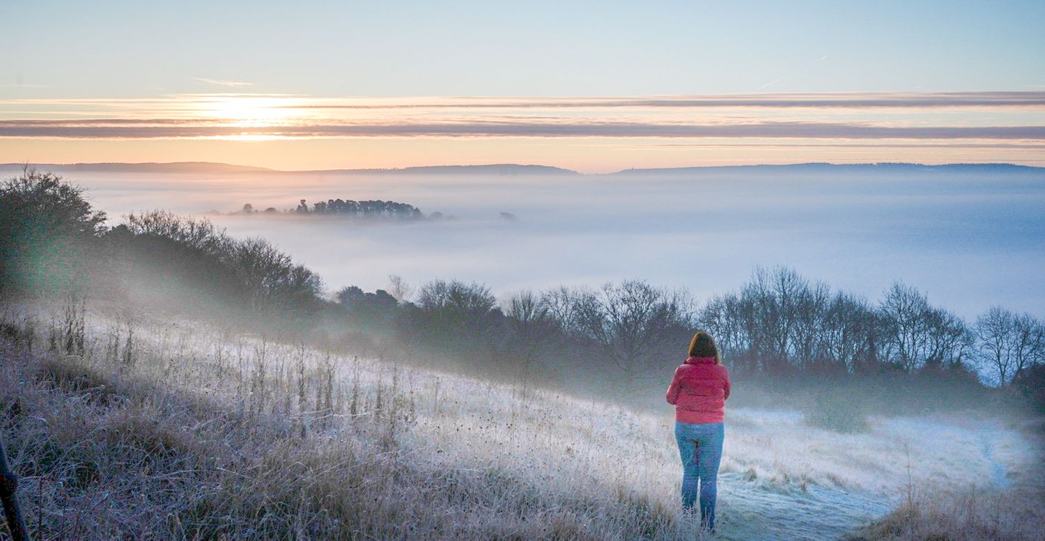Woman watching the sunrise, Newlands Corner, Surrey,