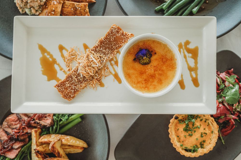 Multiple elegant plated dishes including crème brûlée and savoury tarts on a white tablecloth. SIX84 Photography, Food Photography, Sydney